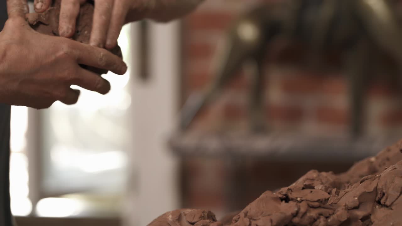 un primer plano de un alfarero amassando arcilla antes de moldear. un escultor masculino está tomando arcilla para crear esculturas de cerámica en el estudio