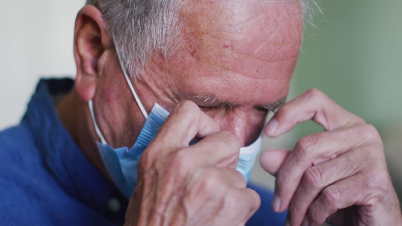 retrato de un hombre caucásico mayor con una máscara facial ajustando la máscara para cubrir su nariz
