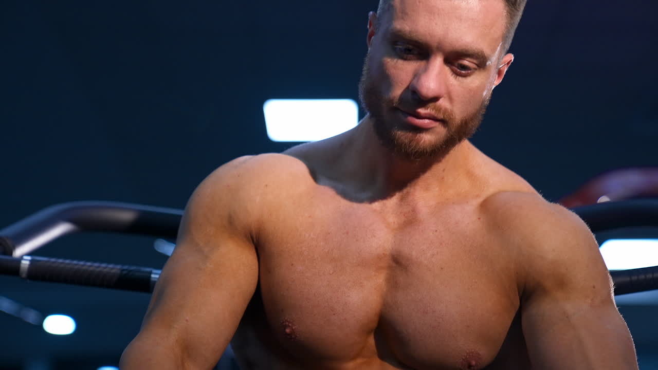 Athlete with strong body posing on gym background. Perfect man`s body. Slow motion.