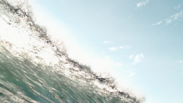 Slow motion cresting wave with harsh light revealing translucent texture