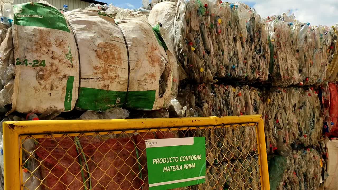 Panning clip showing organised bales of plastic waste at recycling centre