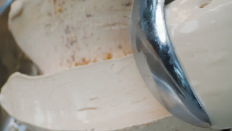 a close-up of a creamy hazelnut ice cream infused with eucalyptus being scooped out using a metal scoop. it has a smooth texture, herbal aroma, and an artisanal look.