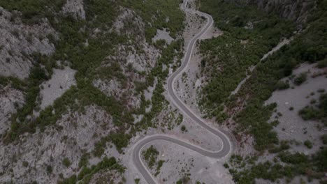 Drone-video-of-a-previous-revealing-plane-on-the-Sh20-highway-in-Albania,-at-the-height-of-Javor-and-Mreg,-snake-road,-car-can-be-seen-circulating,-cloudy-sky