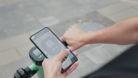 persona que utiliza un teléfono inteligente para alquilar un scooter eléctrico