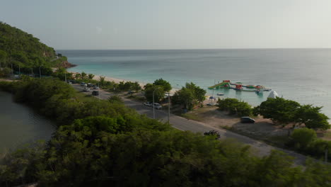 Aerial-tracking-side-view-tourist-in-open-roof-4x4-vehicle-drives-in-scenic-tropical-Antigua-and-Bermuda-coast