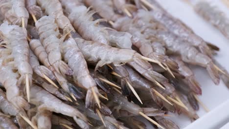 prawns on a wooden stick lie in a large plate