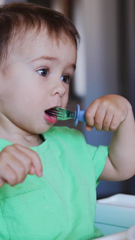 beautiful little kid licks the fork. baby notices something and asks for it with gestures. blurred backdrop. vertical video