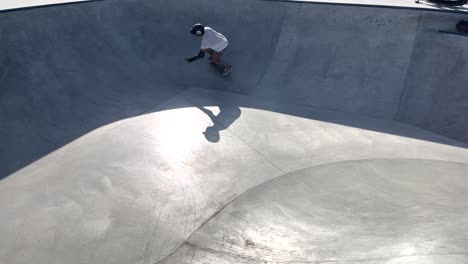 A-skilled-and-athletic-skateboarder-descends-the-ramp-in-the-middle-of-the-pool