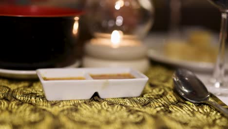 a serene dining setup in phuket, thailand, featuring a candlelit table with sauces, creating a warm and inviting atmosphere