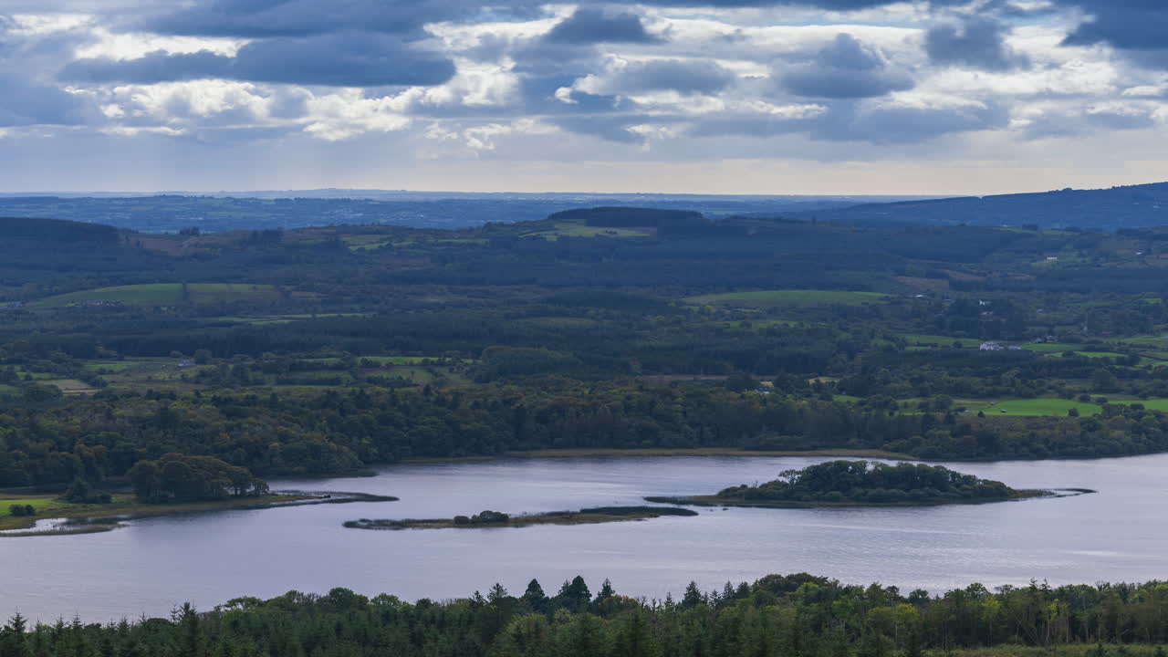Time lapse of rural farming landscape with lake, forest and hills during a cloudy day viewed from above Lough Meelagh in county Roscommon in Ireland