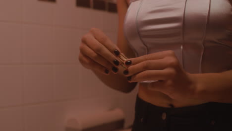 cerca de una mujer irreconocible abriendo un pintalabios en un baño de bar