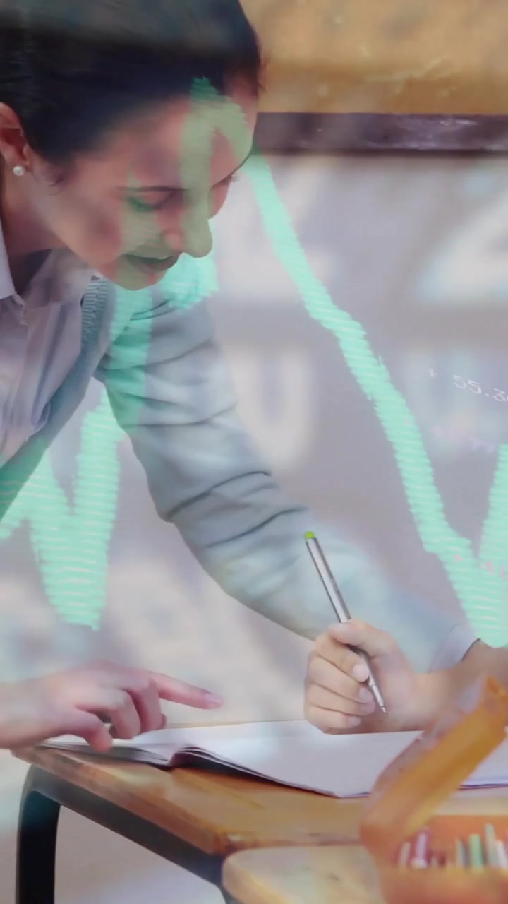 Video verticale: Bambino che scrive, con un tutor che guida la matita per aiutarlo, una sovrapposizione grafica color verde acqua sulla classe
