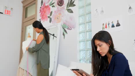 fashion designer working on tablet and a fabric on dress makers model 4k