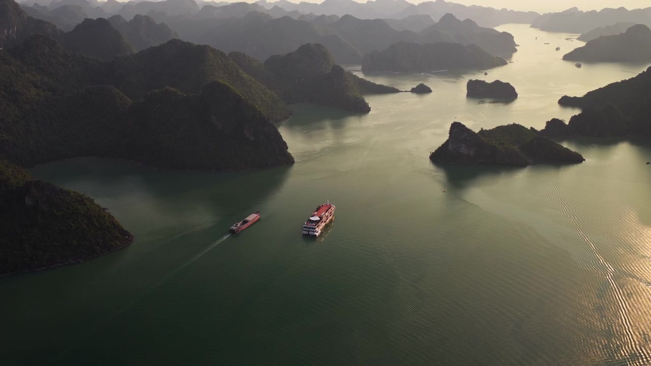 Tàu du lịch và sà lan di chuyển trên Vịnh Hạ Long lúc hoàng hôn tại Việt Nam. - cảnh quay từ trên cao
