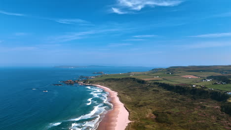 mesmerizing white waves arrive the narrow sandy beach. rocky landscape of coastal area of ireland dwelled by some people. top view.
