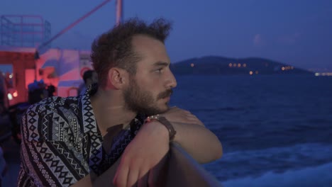 young man traveling on a night ferry looking at the sea.