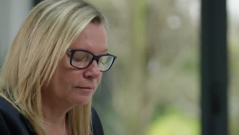 close up of woman working in home office with garden behind, camera move left to right