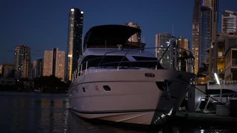 a yacht docked with city skyline at night