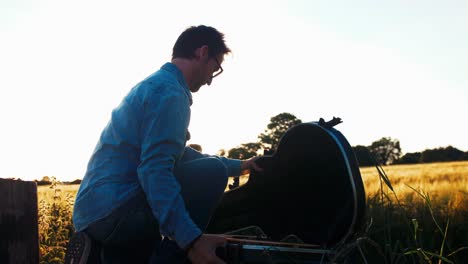 Musician-opens-guitar-case-at-sunset-golden-hour-cinematic