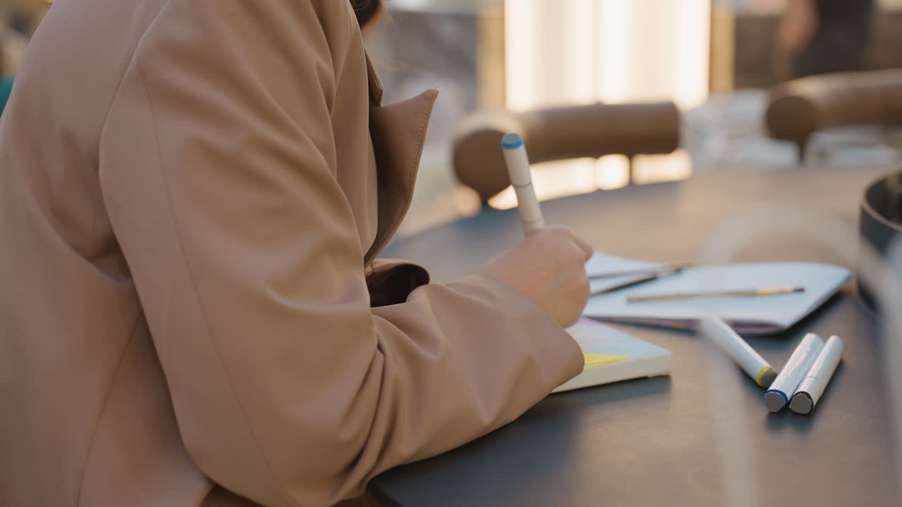 sketching concepts on paper, caucasian hands actively illustrating ideas on paper in public space, individuals engaged in detailed concept sketching at shopping mall table with markers