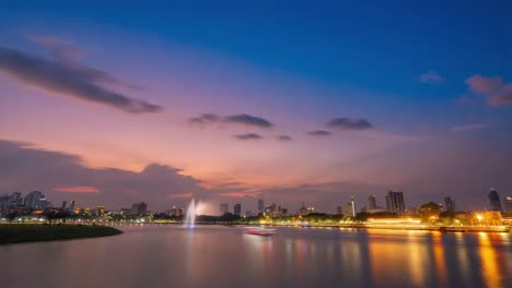 city skyline at night with illuminated fountain and water reflection