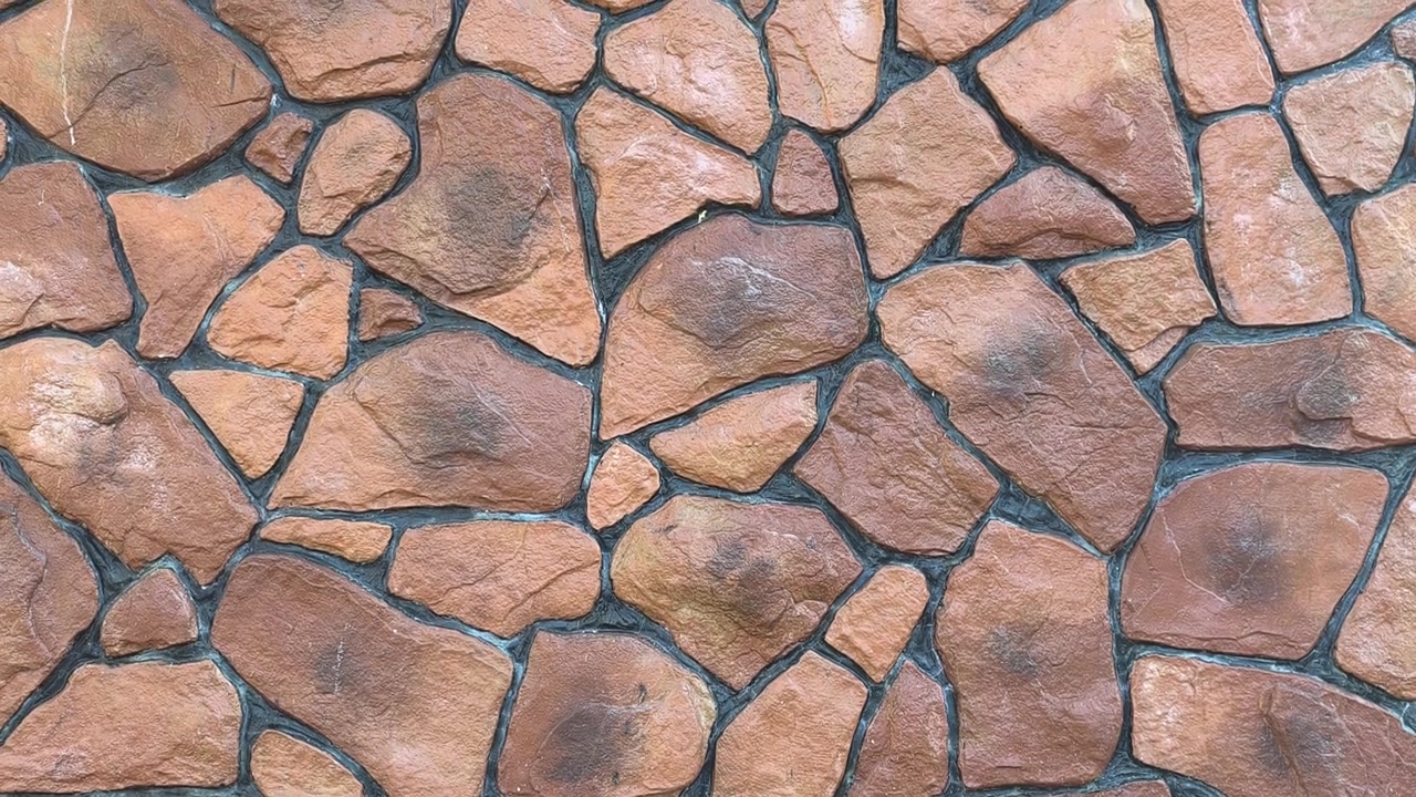 A modern wall features a random pattern of faux stones. Crafted from cement and concrete, they are realistically painted. This durable cladding delivers a stylish, rustic architectural finish.