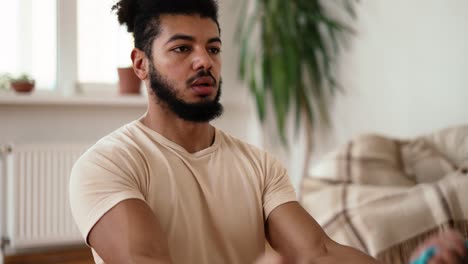 mixed race sportsman is training with rubber bands, tensing muscles of arms