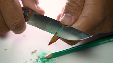 Footage-of-hands-slowly-sharpening-a-pencil-and-some-coloured-pencils-with-a-sharp-knife