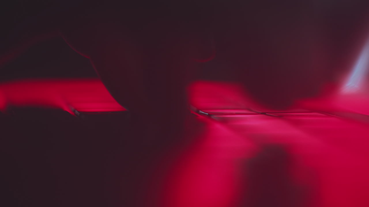 Person Typing on Laptop with Red Light