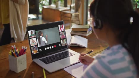 chica haciendo la tarea y teniendo una videoconferencia con el maestro y los compañeros de clase en la computadora portátil en casa