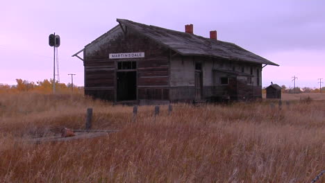 an old station house sits in a field near a railroad track