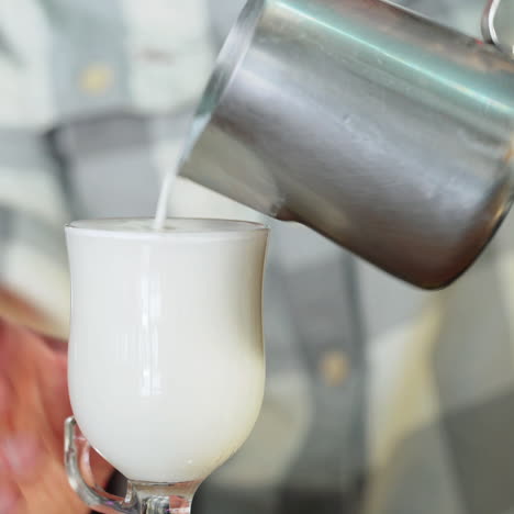 barista pours milk into a glass. sqare video
