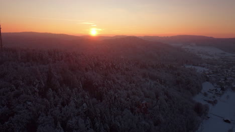 warm read sunrise over a snowy winter forest in the hills of winterthur