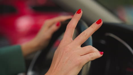 Woman-puts-hands-on-steering-wheel-tapping-fingers-to-music