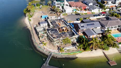 drone footage captures a sunny, high-angle view of residential house construction along a canal in gold coast, australia, with smooth lateral camera movement