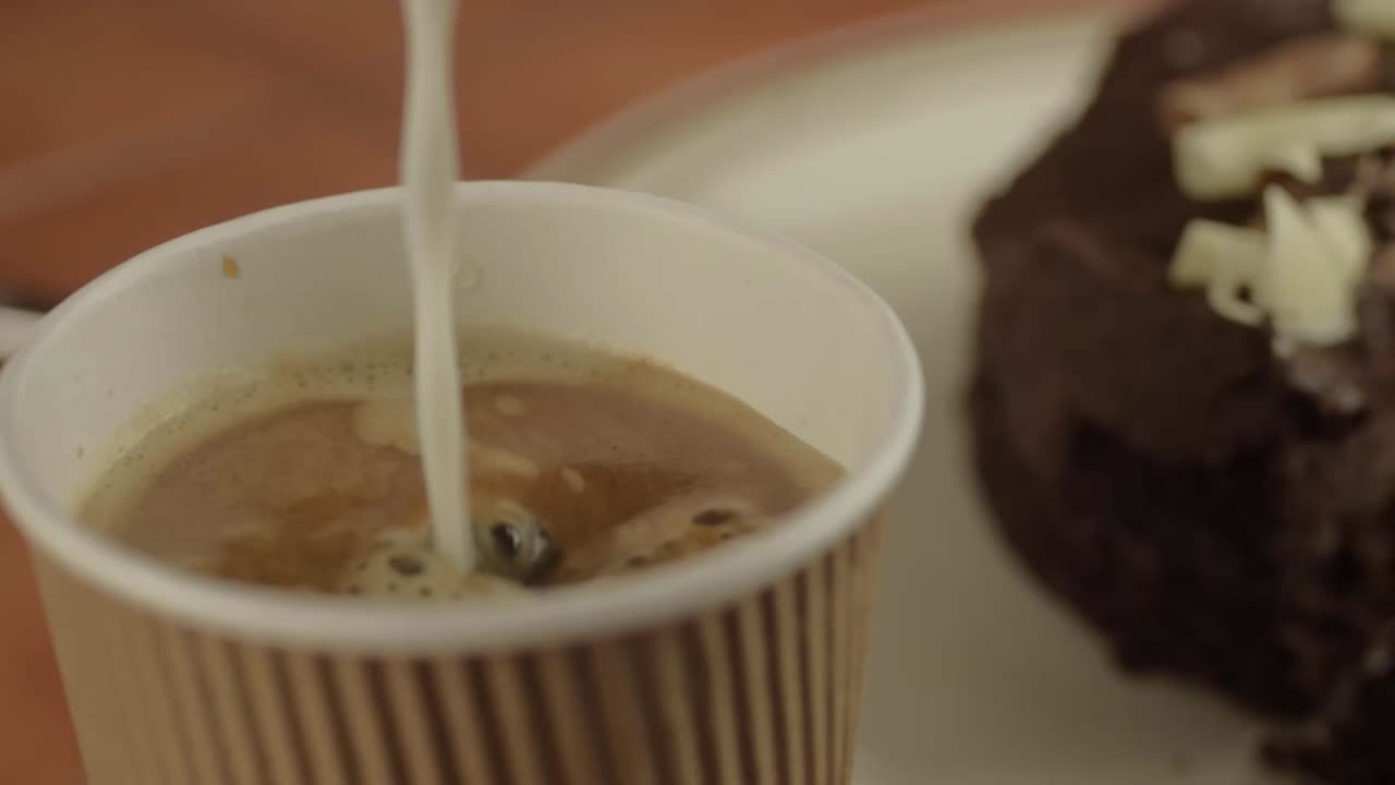 Pouring milk into freshly brewed coffee close up shot