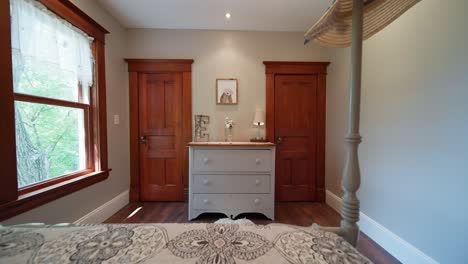 push in shot of a dresser in a bedroom decorated with a large letter e and vase and a lamp