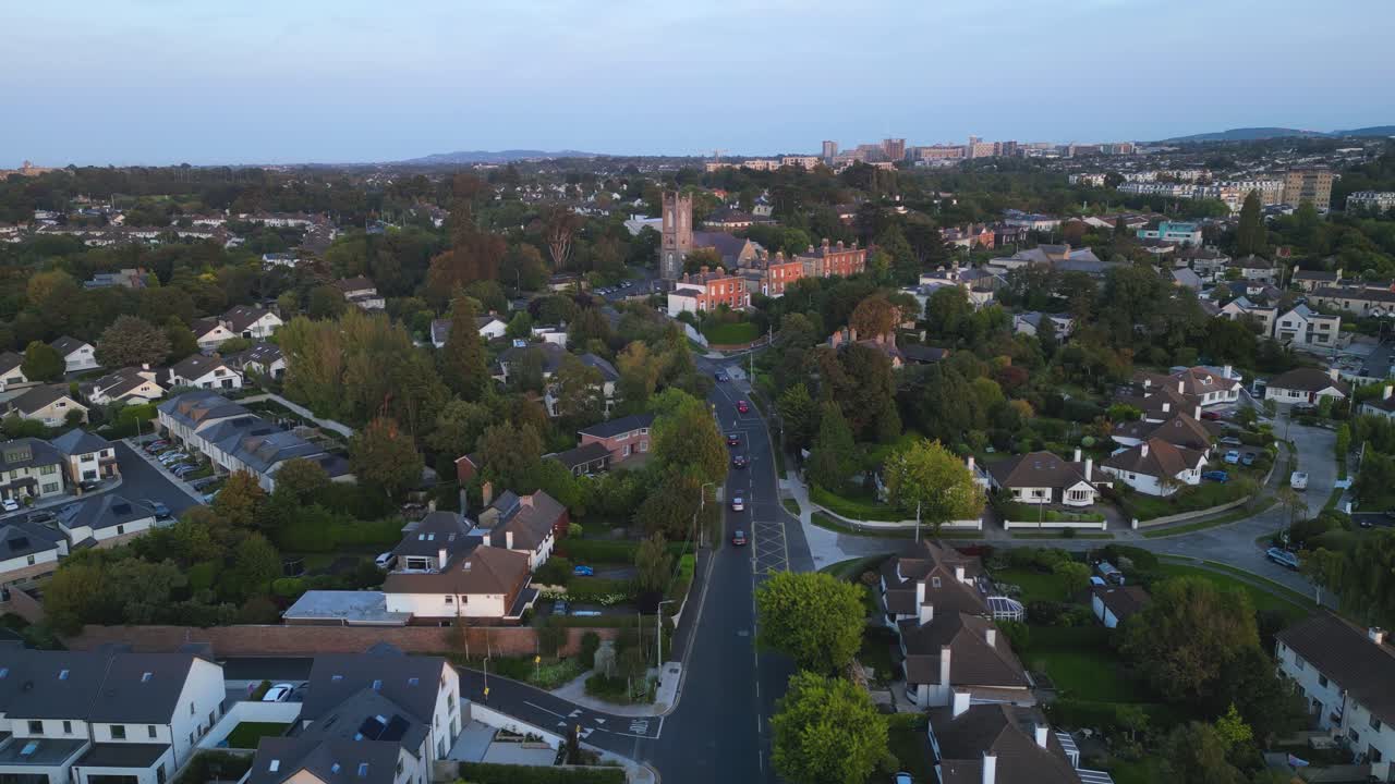 Vista aerea di Taney Road a Dundrum durante l'ora di punta con Christ Church, chiesa parrocchiale di Taney sullo sfondo durante la sera - Dublino Sud, Irlanda.