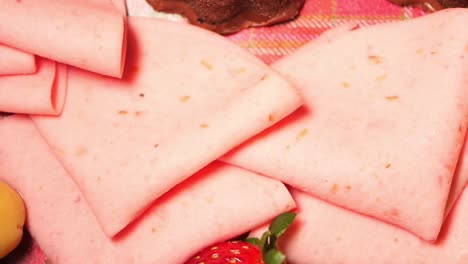 pink sliced ham on a platter with fruit and chocolate