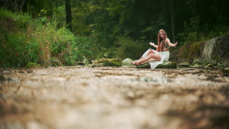 woman meditating seeking inspiration and peace against the background of forest and river