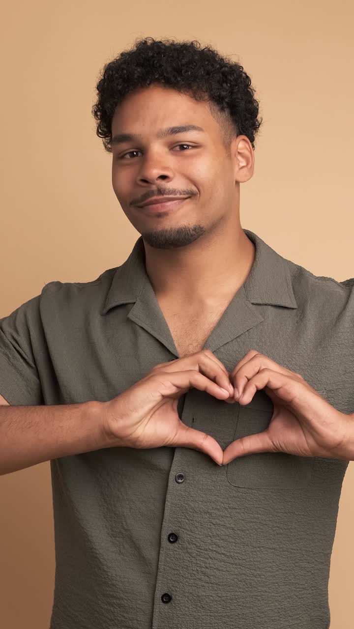 Cheerful man making heart shape sign with hands to show affection