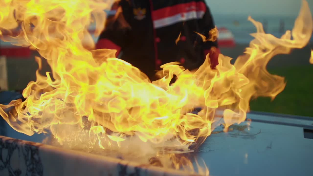 The cook pours oil on the grill with the art of teppanyaki. and flames come out.