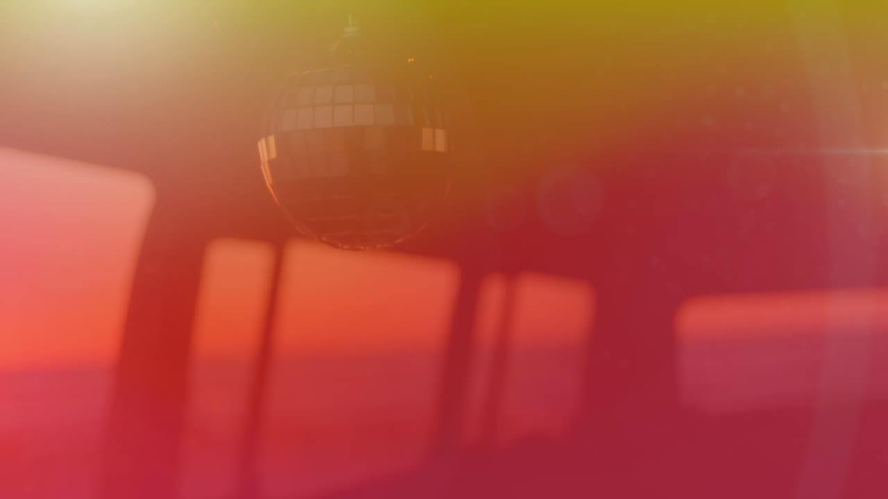 태양이 지는 배경으로 노란색에서 빨간색으로 바람에 움직이는 거울 공의 애니메이션