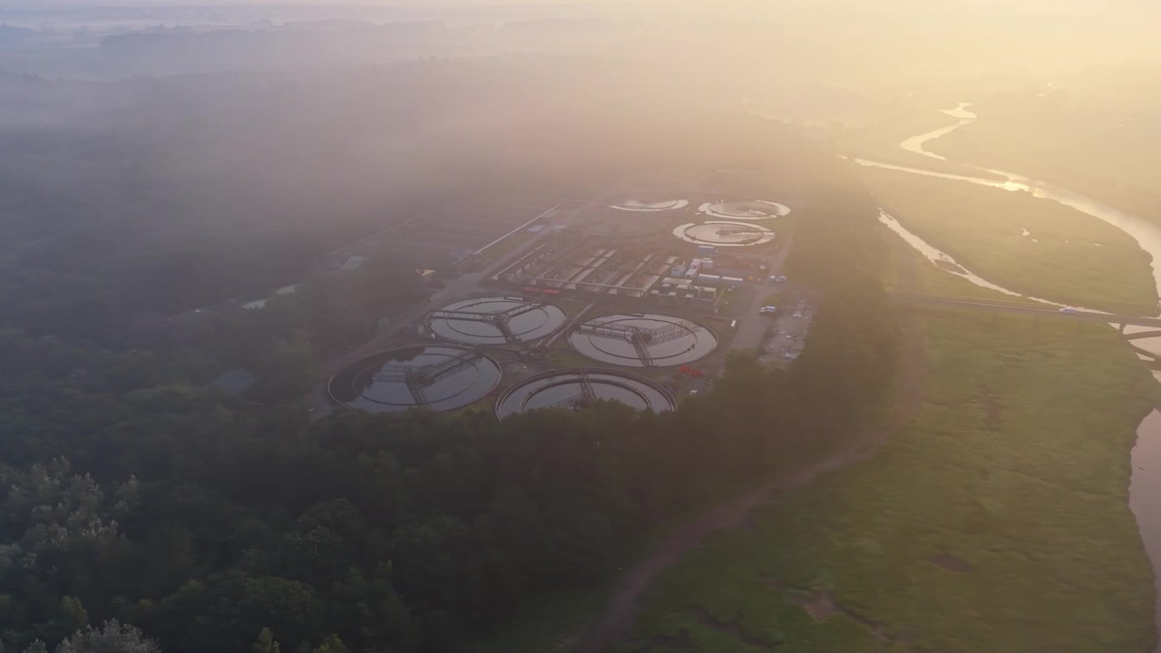 Aerial Orbit of Water Treatment Plant and wastewater recycling facility at sunrise. Misty Morning View. Clean tech, sustainability, and environmental engineering concept.