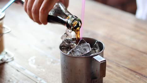 sequence of pouring soda over ice cubes in a glass.