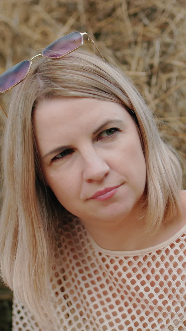 женщина в сетчатой ткани с солнцезащитными очками испытывает отражающий момент, слегка наклоняя голову, когда она смотрит в даль, в сопровождении другой женщины, смотрящей вперед в огромном открытом поле