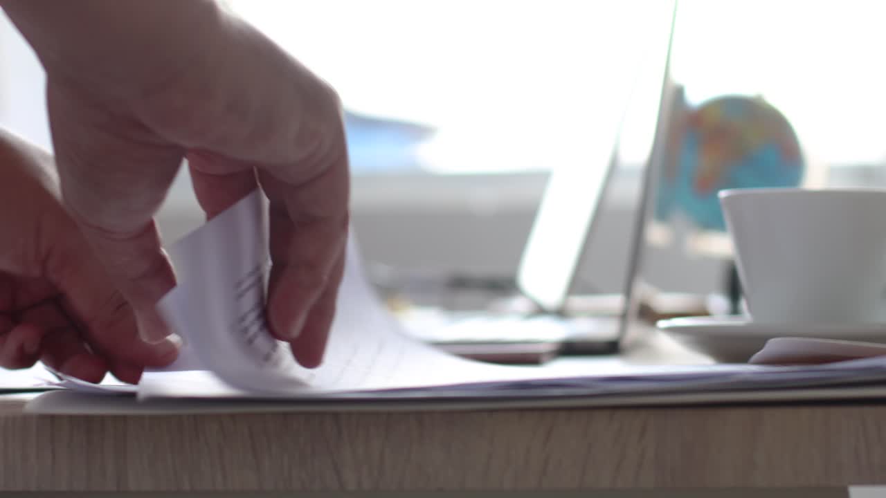Businessman hand flipping pages of document paper in the office desk