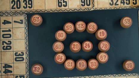 primer plano cinematográfico, inclinación suave hacia abajo, disparo desde arriba de un bingo, barriles de madera en un círculo, figuras de madera, fondo de números antiguos, juego de mesa vintage, iluminación profesional, cámara lenta 120 fps