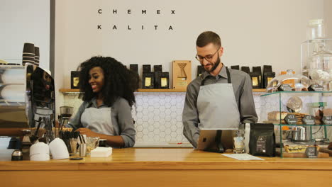 barista afroamericana y compañero de trabajo caucásico trabajando en una cafetería moderna