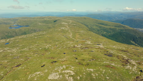 Drone pushing in over Vidden plateau, revealing lush green meadows and panoramic mountain views